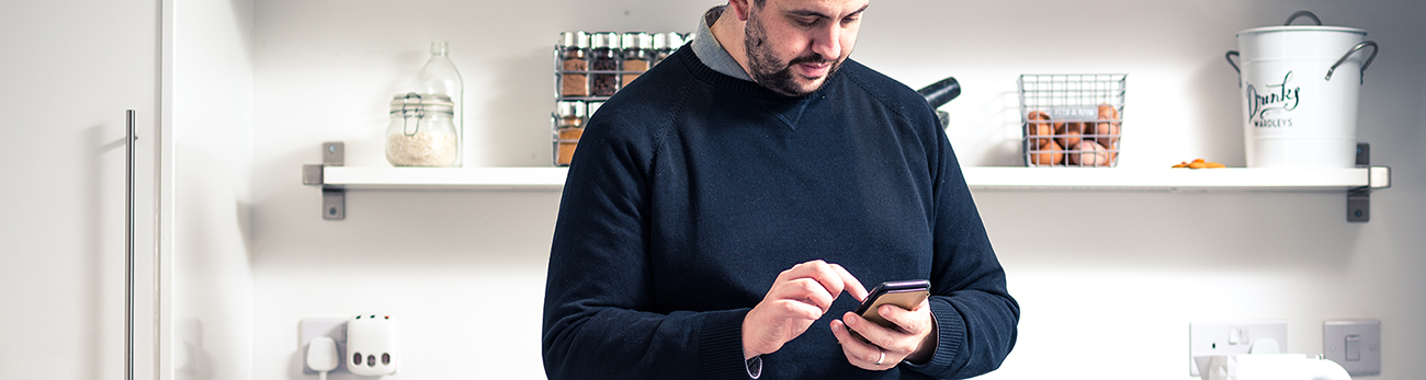 man holding mobile phone in kitchen