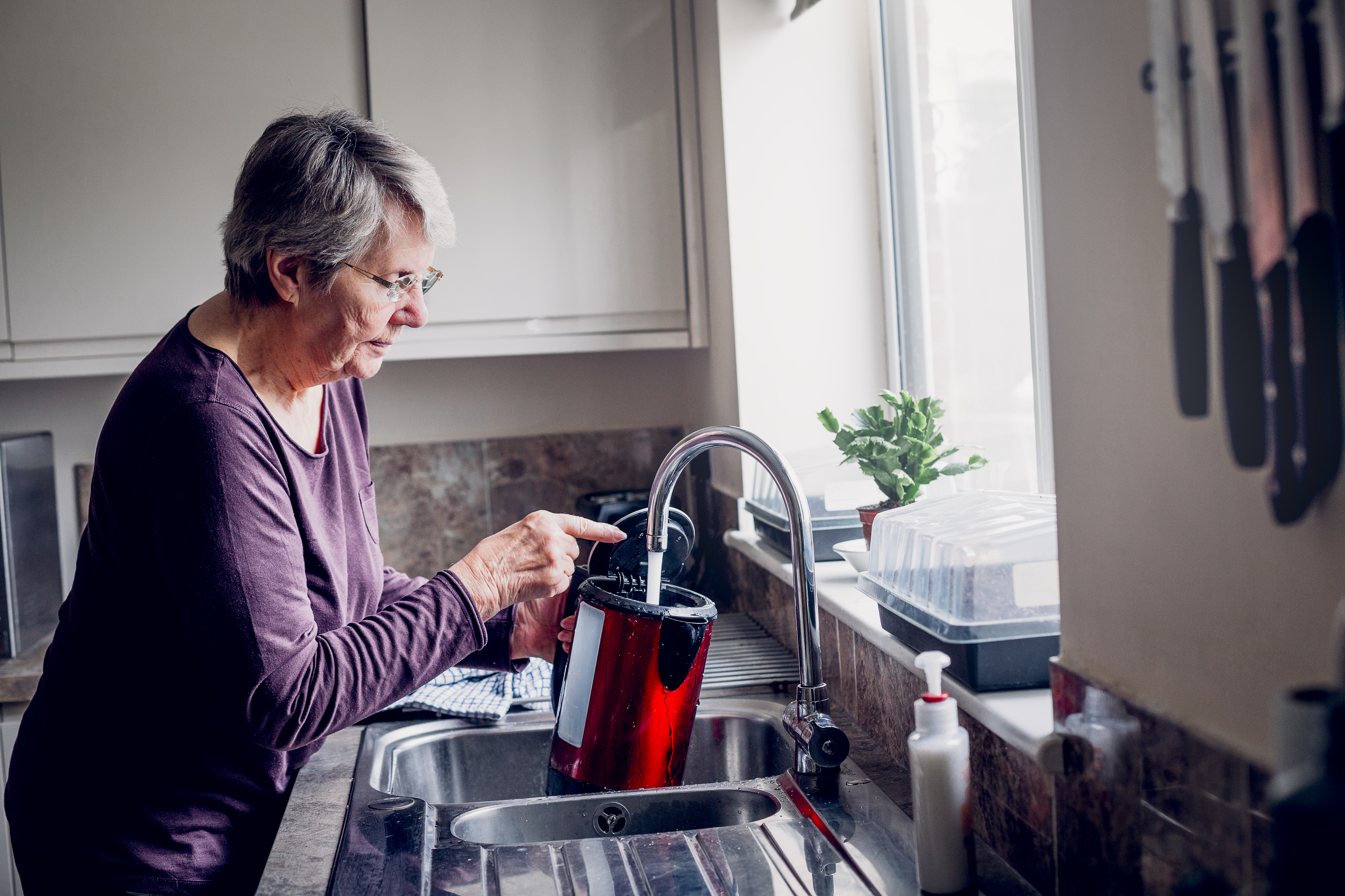 women filling kettle kitchen sink