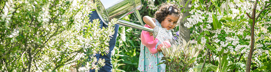 girl watering plants with watering can