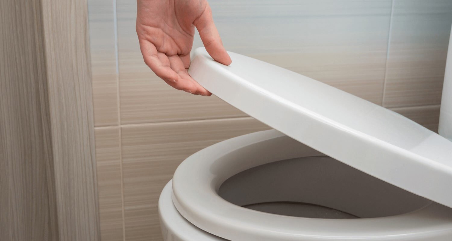 Hand putting down the toilet seat