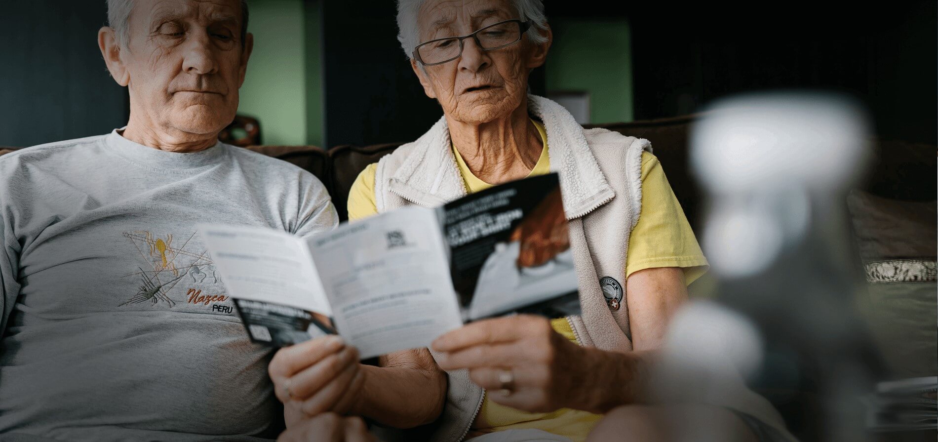 Elderly couple on couch reading a leaflet