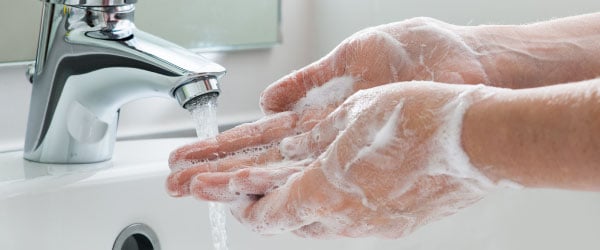 hands covered in soap under running tap